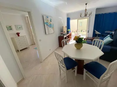 a dining room and living room with a table and chairs at Modern 2BR Vilamoura Stay Pool Access Golf Nearby 15 Percent Off in Quarteira