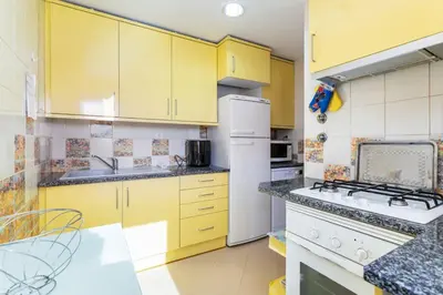a kitchen with yellow cabinets and a white refrigerator at Marina Paradis Bleu in Albufeira
