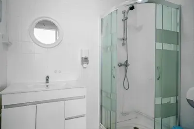 a white bathroom with a sink and a shower at Plaza Inn Hostel & Rooms in Faro