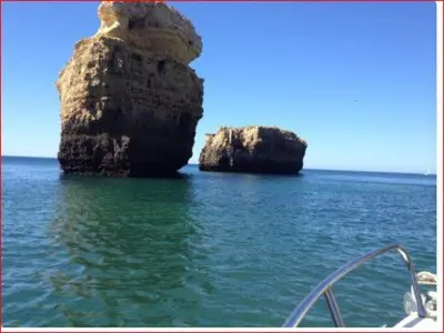 two large rocks in the water next to a boat at Vista das Ondas in Albufeira