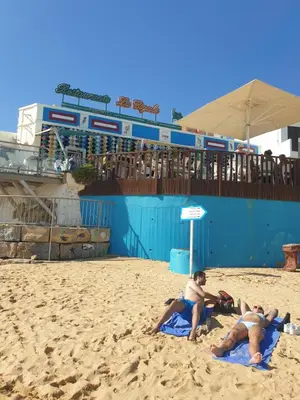 three people laying on towels on a beach at Vista das Ondas in Albufeira