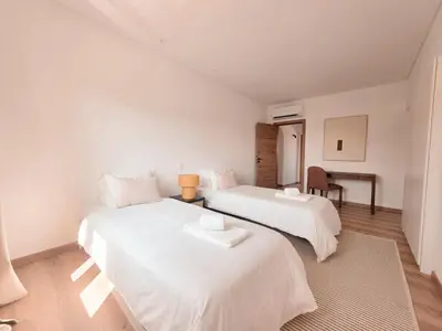 two beds in a room with white walls and wooden floors at Casa Shiva in Albufeira