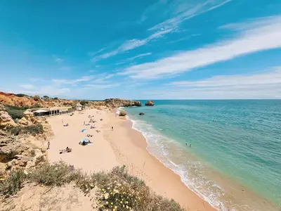 a beach with people on the sand and the water at Casa Shiva in Albufeira