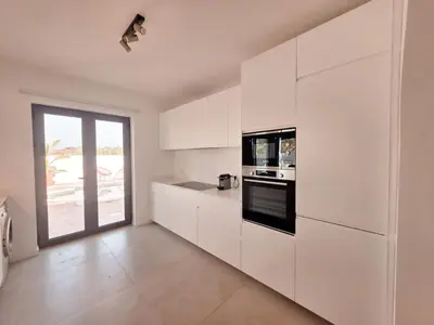 a kitchen with white cabinets and a large window at Casa Shiva in Albufeira