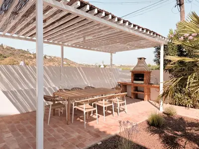 a wooden table and chairs under a white pergola at Casa Shiva in Albufeira