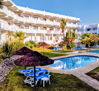 a hotel with chairs and an umbrella next to a swimming pool at 1- bedroom flat in Vilamoura near the beach in Vilamoura