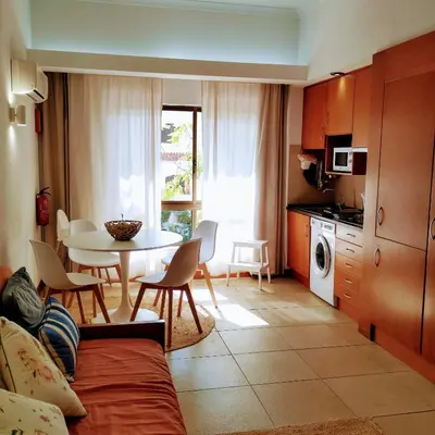 a living room with a table and a kitchen with a dining room at 1- bedroom flat in Vilamoura near the beach in Vilamoura