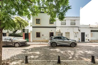 two cars parked in a parking lot in front of a building at Casa dos Quatro in Faro