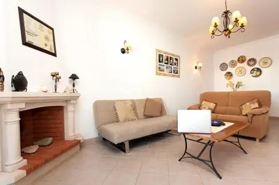 a living room with a couch and a table at Os Apartamentos A Ramos na Praia da Galé Estão inserido em Condomínio com PISCINA, Fica apenas a 350 Metros da Praia da Galé - Apartamentos com Ar Condicionado tanto nos Quartos como na Sala, Smart TV com Prime Vídeo e Cozinha Completa in Albufeira