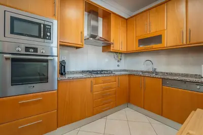 a kitchen with wooden cabinets and a microwave at Sunny House with Jacuzzi and Pool by HostWise in Albufeira
