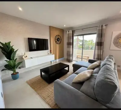 a living room with a gray couch and a tv at Pine Hills Vilamoura in Quarteira