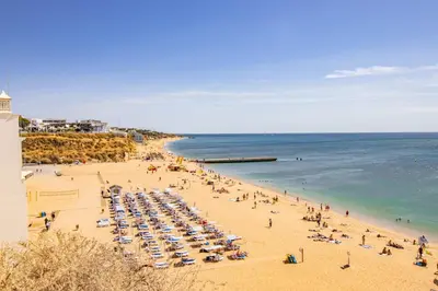 a beach with a lot of people and the ocean at Charming Old Town 1BR 50m from Beach AC Wi-Fi Parking in Albufeira