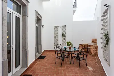 a patio with a table and chairs on a brick floor at Blife Galya private house in Faro