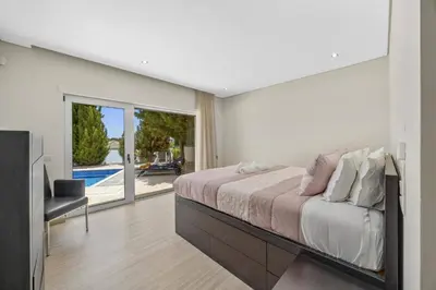 a bedroom with a large bed and a sliding glass door at Villa Caripira by Villa Plus in Albufeira