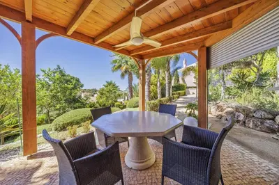 a patio with a table and chairs and a ceiling fan at Villa Caripira by Villa Plus in Albufeira
