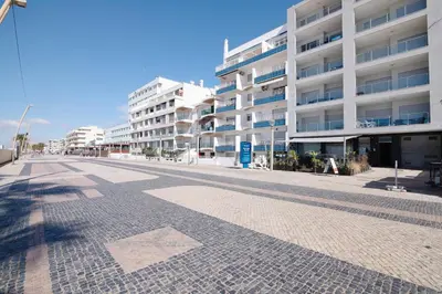 a hotel room with two beds and a hallway at Quarteira Modern Flat in Quarteira