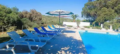 a row of blue chairs and an umbrella next to a swimming pool at Quinta do Lagar - 02 in Albufeira
