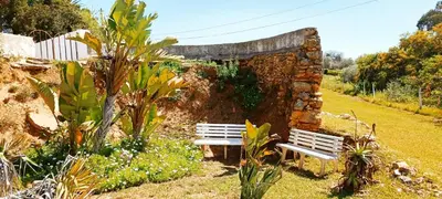 a stone wall with two benches in a garden at Quinta do Lagar - 03 in Albufeira