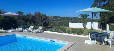 a swimming pool with chairs and a table and an umbrella at Quinta do Lagar - 04 in Albufeira