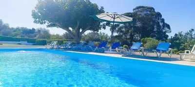 a group of chairs and an umbrella next to a swimming pool at Quinta do Lagar - 06 in Albufeira