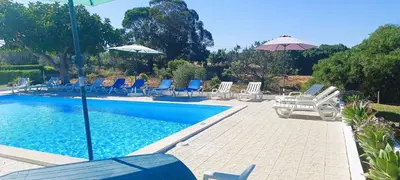 a swimming pool with chairs and umbrellas and a group at Quinta do Lagar - 07 in Albufeira