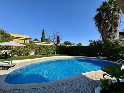a chair and an umbrella next to a swimming pool at Albufeira Summer Villa 3 With Pool by Homing in Sesmarias