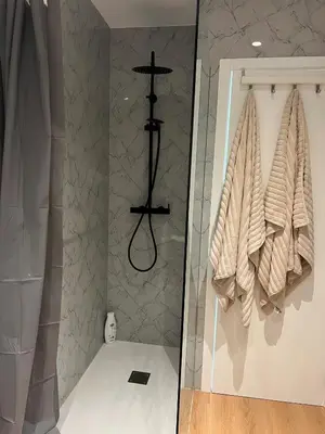 a bathroom with a shower with towels on a wall at Ocean View Apartment Steps to Beach Vil15m Faro25m in Quarteira