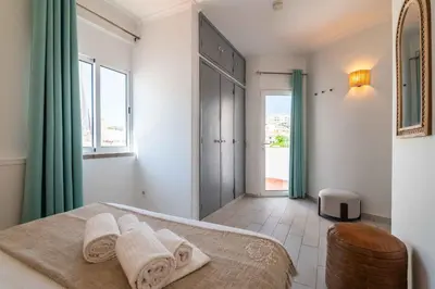 a white bedroom with a bed and a window at Downtown Rooftop 1 Bedroom Apartment in Albufeira