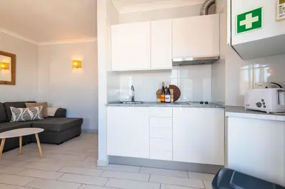 a kitchen with white cabinets and a living room at Downtown Rooftop 1 Bedroom Apartment in Albufeira