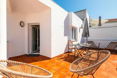 a patio with chairs and a table and an umbrella at Downtown Rooftop 1 Bedroom Apartment in Albufeira