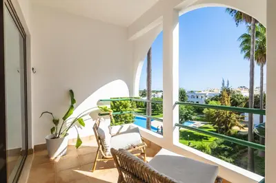 a balcony with a view of a pool and palm trees at Casa Alonso 2 Bedroom Apartment with Pool in Albufeira