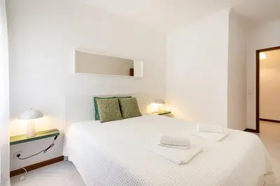 a white bedroom with a white bed with two towels on it at SunnyQuarters WalktoBeach 2BR AC