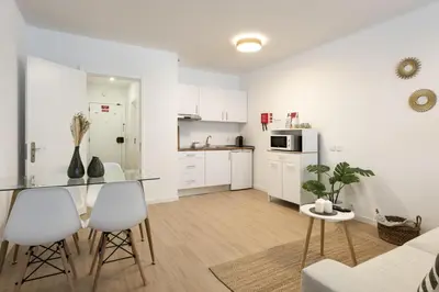 a kitchen with white cabinets and a table and chairs at Maya Vilamoura - City center by HD PROPERTIES in Vilamoura