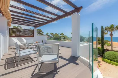 a patio with white chairs and a view of the ocean at Golf&Mar By Garvetur Villas in Loulé