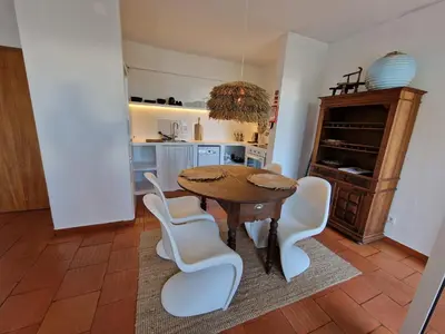 a kitchen with a wooden table and white chairs at Incrível T1 na praia da Oura in Albufeira
