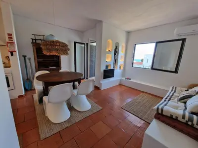 a living room with a table and white chairs at Incrível T1 na praia da Oura in Albufeira