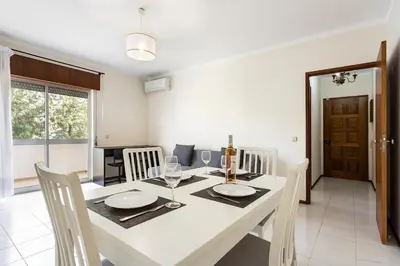 a dining room with a white table and chairs at Amoreira 3br City Center at Homesbyfc in Faro