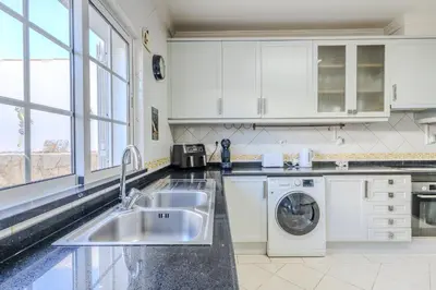 a kitchen with white cabinets and a sink and a dishwasher at #343 Villa with Pool & Jacuzzi by Home Holidays in Albufeira