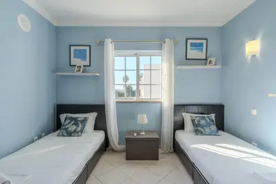 a bedroom with a large white bed with blue pillows at #343 Villa with Pool & Jacuzzi by Home Holidays in Albufeira