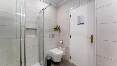 a white bathroom with a toilet and a shower at Bright 1BDR Flat in Albufeira by LovelyStay in Albufeira