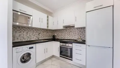 a kitchen with white cabinets and a washer and dryer at Bright 1BDR Flat in Albufeira by LovelyStay in Albufeira