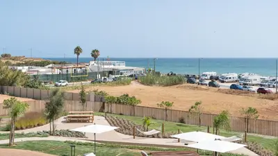 a park with tables and umbrellas and the ocean at Luxury Flats with Pool in Quarteira by LovelyStay in Quarteira