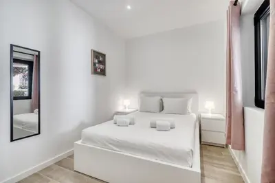 a white bedroom with a white bed and a mirror at Sunshine Apartment in Vilamoura