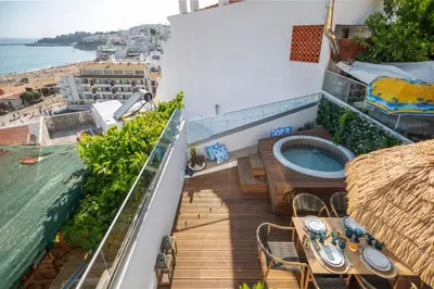 a balcony with a hot tub and tables and a view of the ocean at Micului Refugiu in Albufeira
