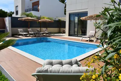a swimming pool with chairs and a couch next to a house at Algarve Boho Beach House in Albufeira