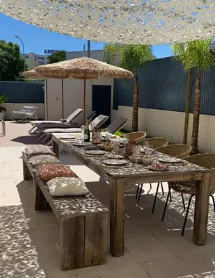 a large wooden table with chairs and an umbrella at Algarve Boho Beach House in Albufeira