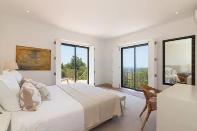 a white bedroom with a bed and a balcony at Casa Velha in Loulé