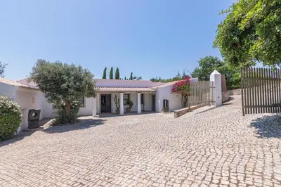 a white house with a gate and a brick driveway at Casa Velha in Loulé