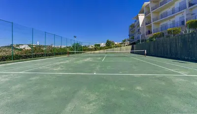a tennis court in front of a building at Luxurious T2 with Pool & Breathtaking Ocean Views by BeCherish in Albufeira