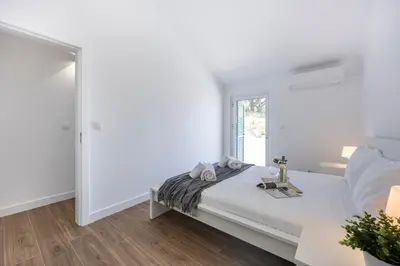 a white bedroom with a bed and a window at Alfamar Beach Apartment in Albufeira
